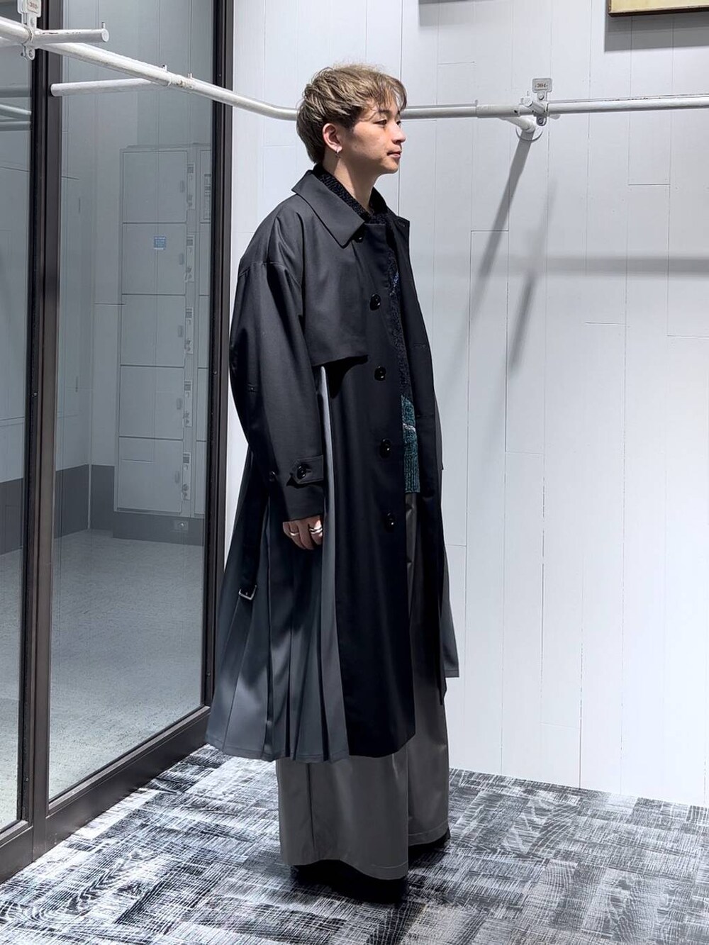 ブラック系のステンカラーコート、ブラック系のニット/セーター、シルバー系のリングを着用したメンズの秋コーディネートの2枚目の写真