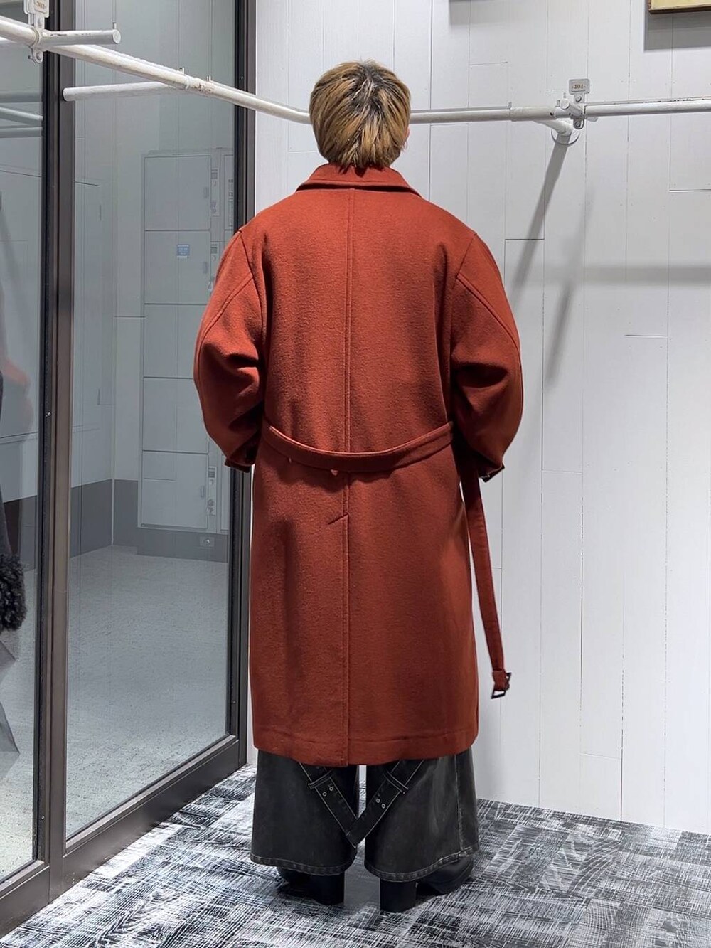 オレンジ系のステンカラーコート、グレー系のカーゴパンツ、ピンク系のカーディガン/ボレロを着用したメンズの冬コーディネートの3枚目の写真