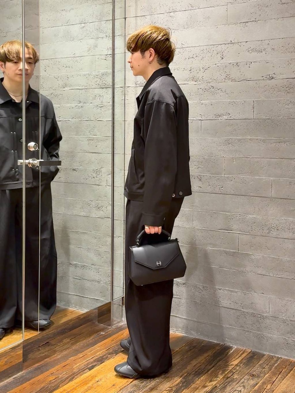 ブラック系のスラックス、ブラック系のブルゾン、ブラック系のショルダーバッグを着用したメンズの春コーディネートの4枚目の写真