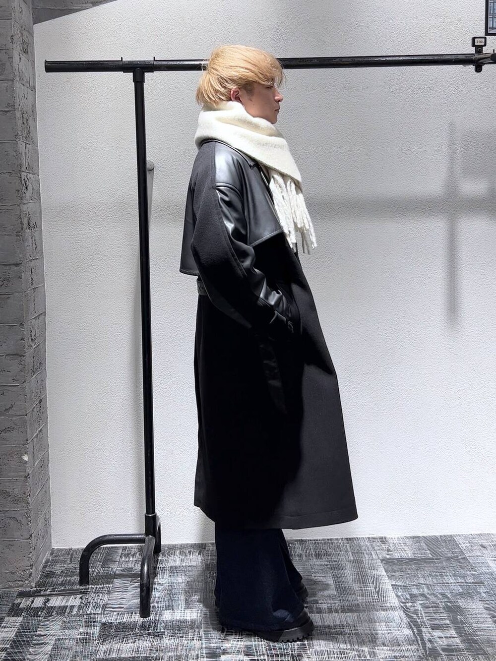 ブルー系のデニムパンツ、ブラック系のトレンチコート、ブラック系のブーツを着用したメンズの秋コーディネートの2枚目の写真