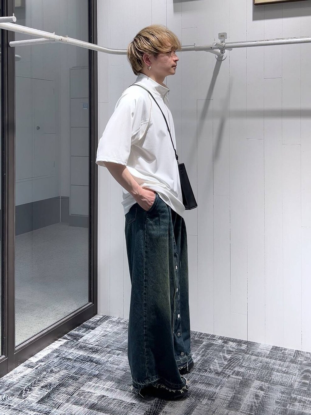 ブルー系のデニムパンツ、ブラック系のショルダーバッグ、ブラック系のドレスシューズを着用したメンズの春コーディネートの2枚目の写真