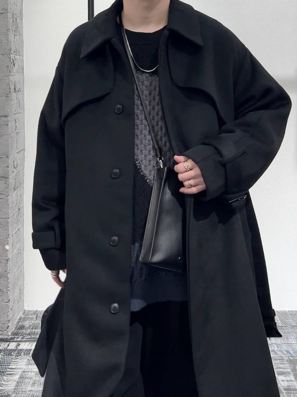 ブラック系のデニムパンツ、ブラック系のステンカラーコート、ブラック系のショルダーバッグを着用したメンズの秋コーディネートの5枚目の写真