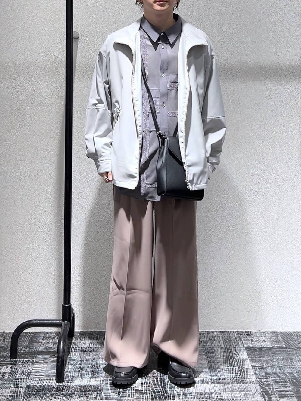 ピンク系のスラックス、グレー系のブルゾン、ブラック系のショルダーバッグを着用したメンズの冬コーディネートの2枚目の写真
