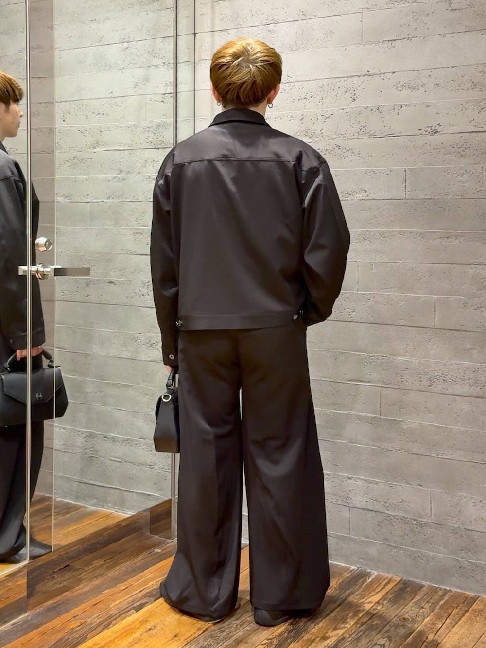 ブラック系のスラックス、ブラック系のブルゾン、ブラック系のショルダーバッグを着用したメンズの春コーディネートの3枚目の写真