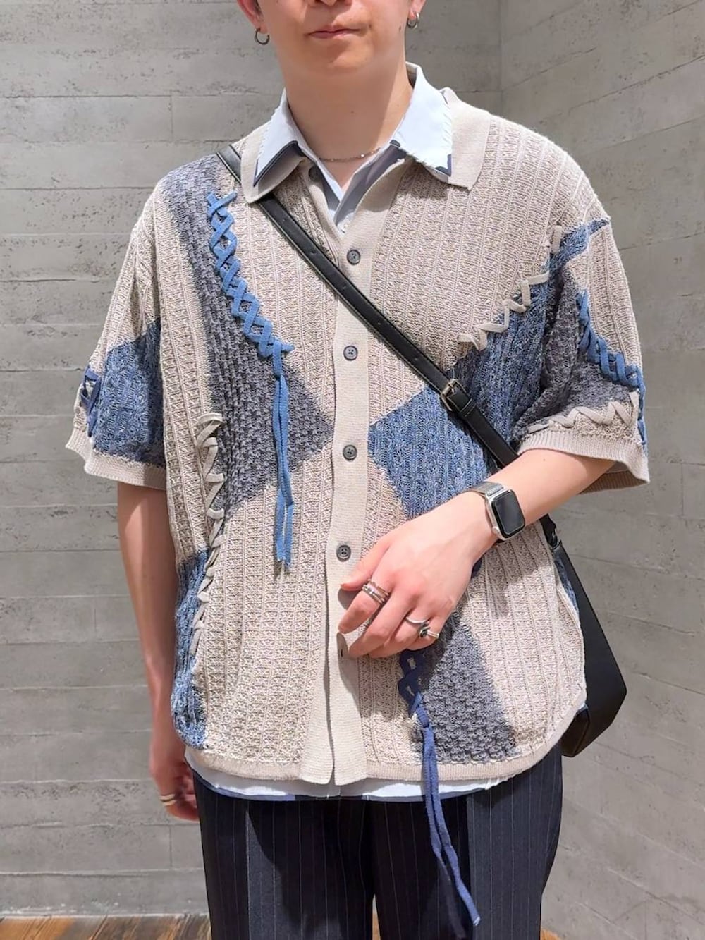 ブルー系のスラックス、ブラック系のドレスシューズ、ブラック系のショルダーバッグを着用したメンズの春コーディネートの5枚目の写真