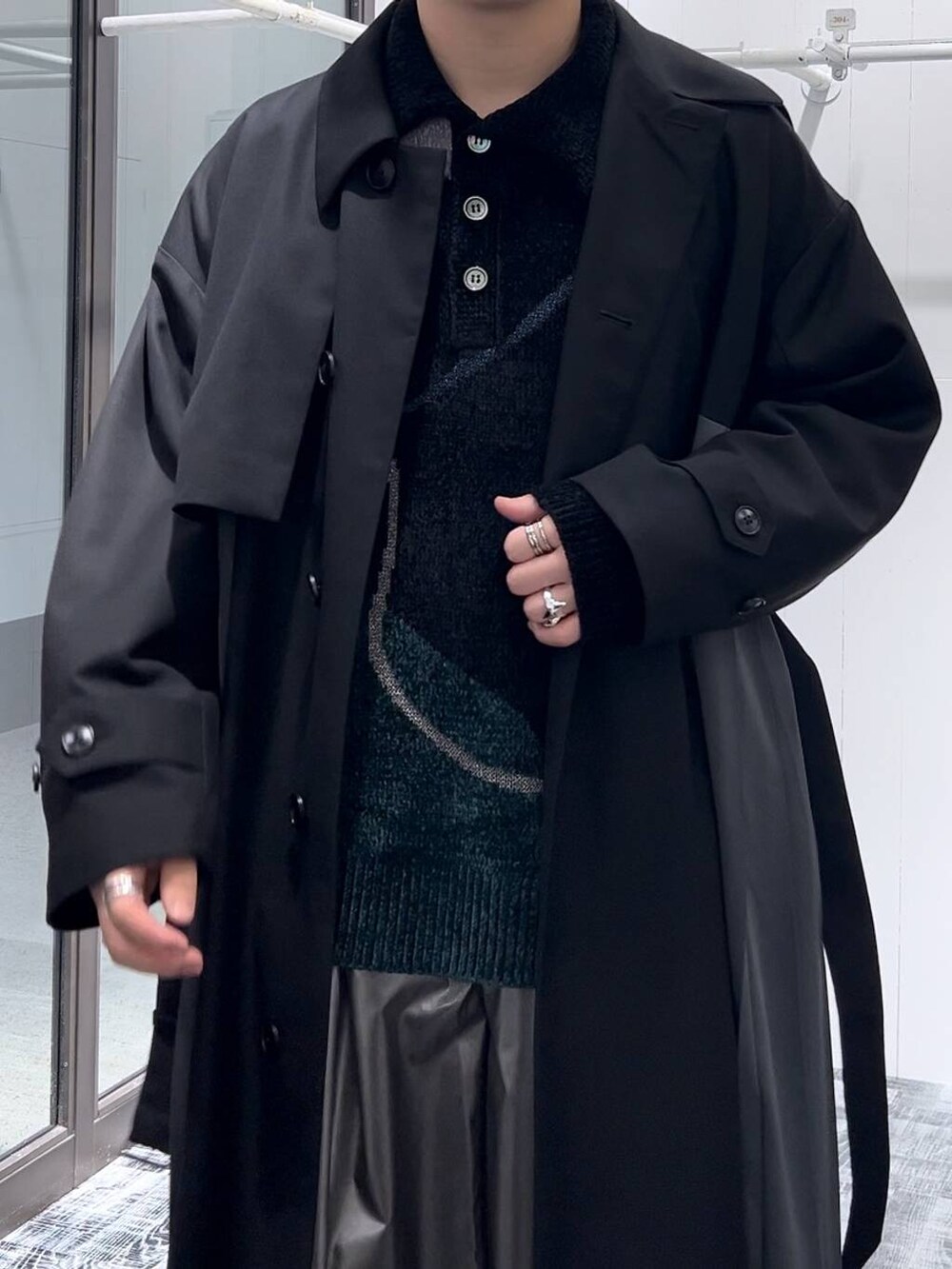 ブラック系のステンカラーコート、ブラック系のニット/セーター、シルバー系のリングを着用したメンズの秋コーディネートの5枚目の写真