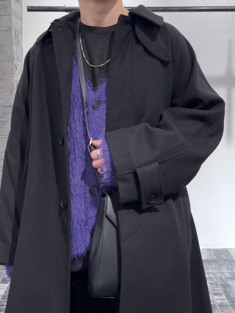 パープル系のカーディガン/ボレロ、ブラック系のステンカラーコート、ブラック系のショルダーバッグを着用したメンズの冬コーディネートの5枚目の写真