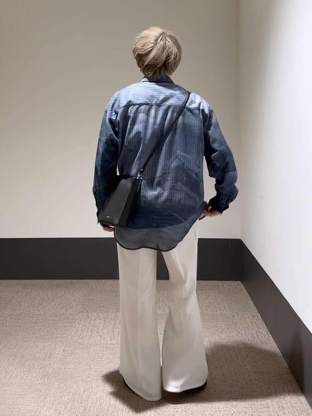 ホワイト系のスラックス、ブルー系のTシャツ/カットソー、ブラック系のショルダーバッグを着用したメンズの冬コーディネートの4枚目の写真