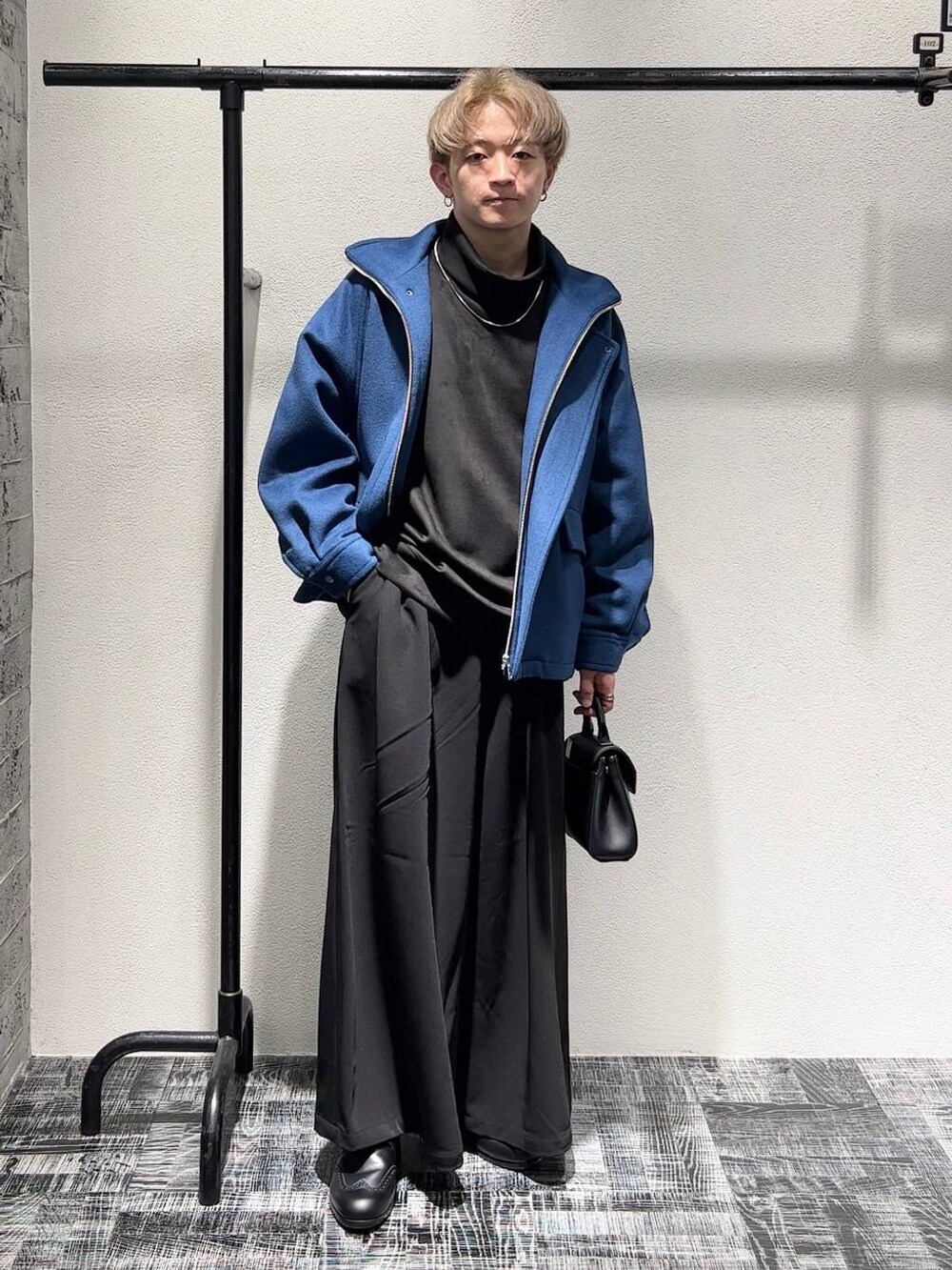 ブルー系のブルゾン、ブラック系のスラックス、ブラック系のショルダーバッグを着用したメンズの秋コーディネートの4枚目の写真