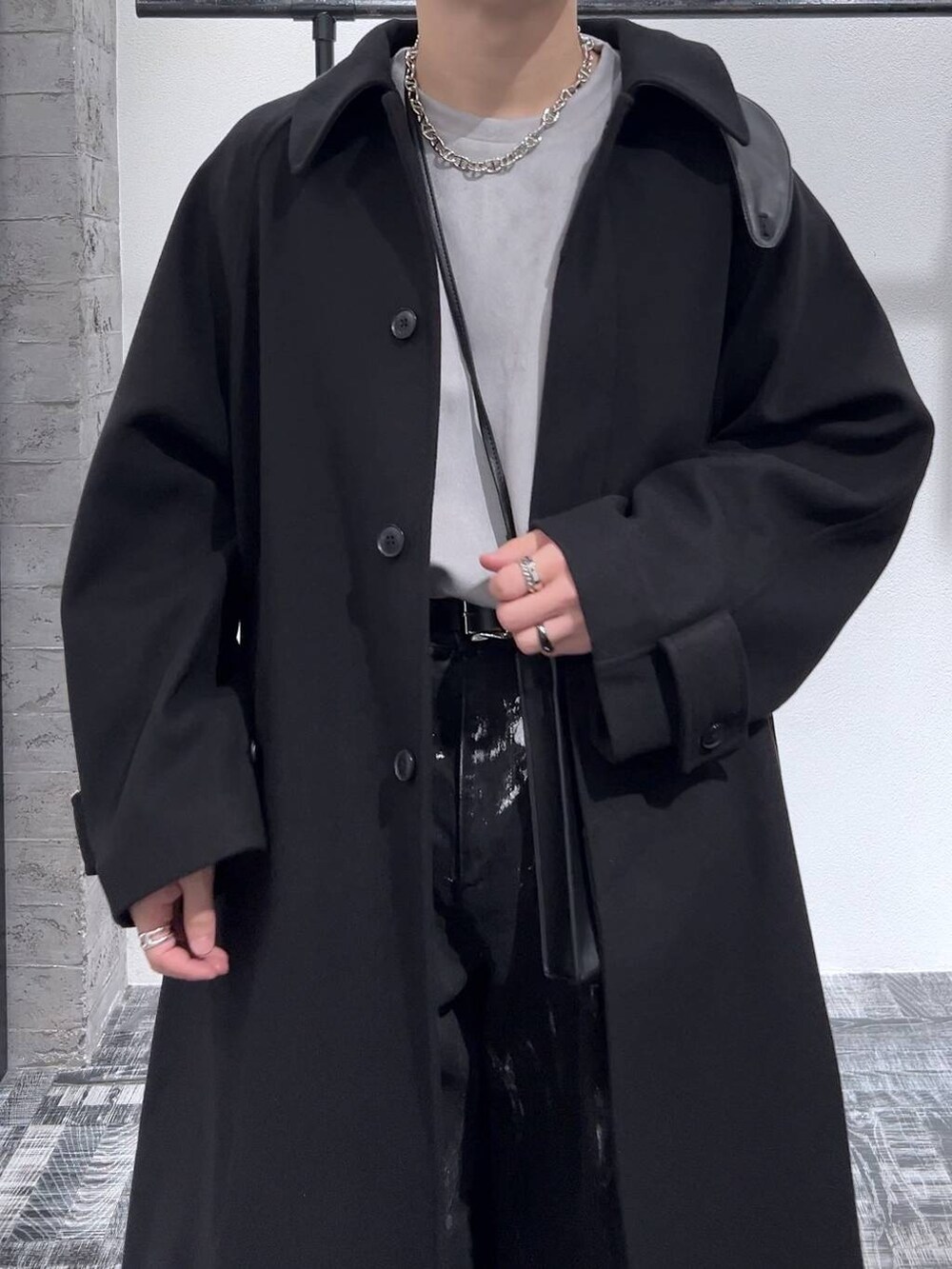 ブラック系のステンカラーコート、グレー系のスウェット、ブラック系のブーツを着用したメンズの冬コーディネートの5枚目の写真