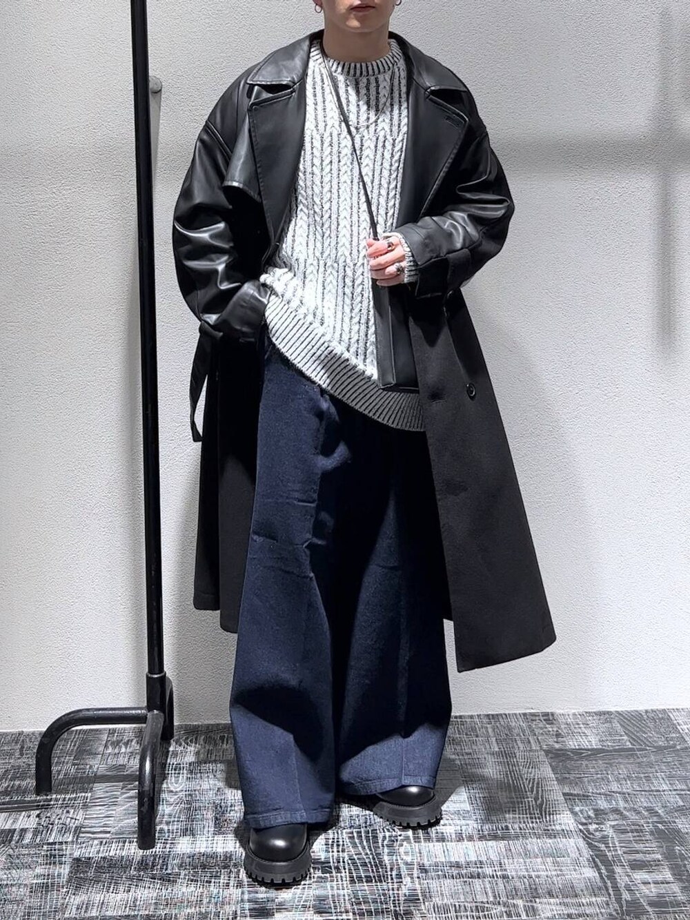 ブルー系のデニムパンツ、ブラック系のトレンチコート、ブラック系のショルダーバッグを着用したメンズの秋コーディネートの2枚目の写真