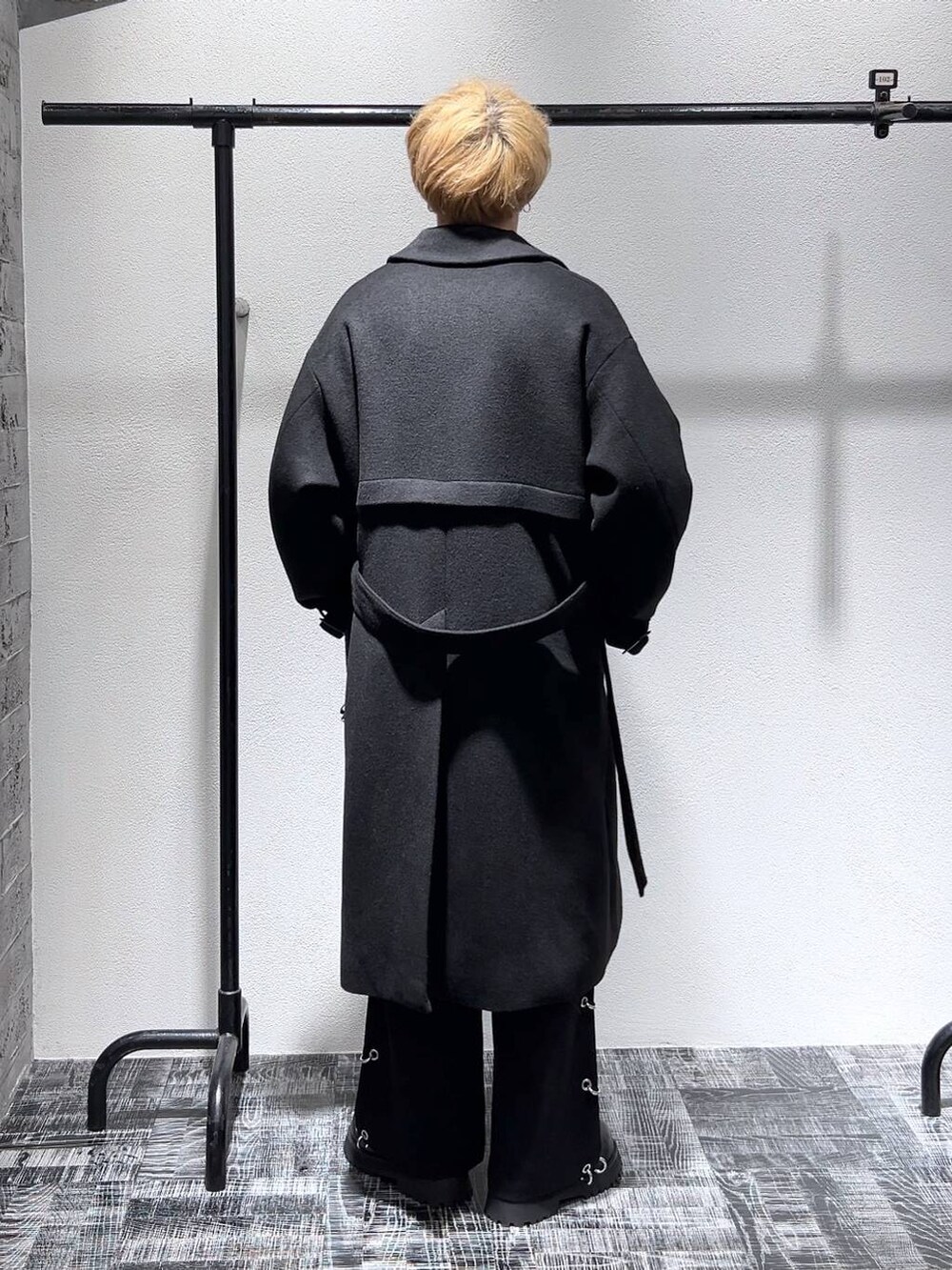 ブラック系のステンカラーコート、ブラック系のブーツ、グレー系のスウェットを着用したメンズの秋コーディネートの3枚目の写真