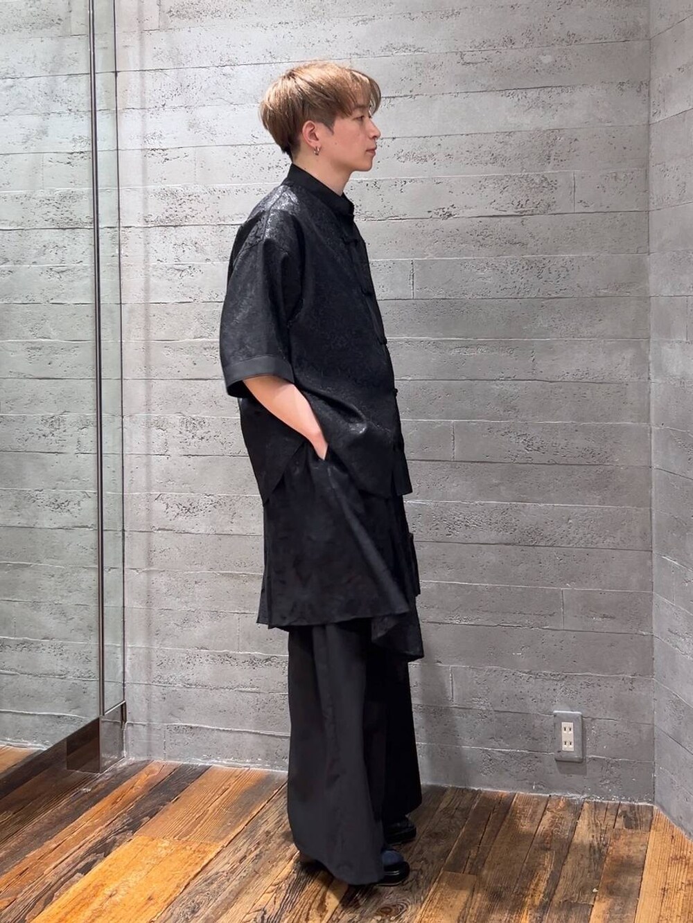 ブラック系のスラックス、ブラック系のハンドバッグ、ブラック系のサンダルを着用したメンズの夏コーディネートの2枚目の写真