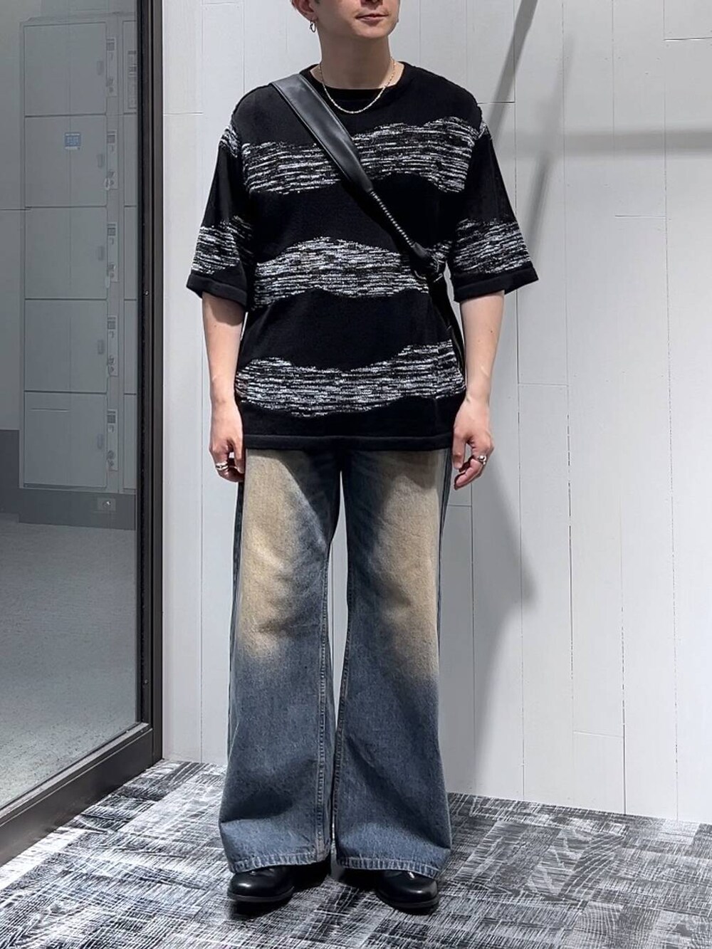 ブルー系のデニムパンツ、ブラック系のショルダーバッグ、ブラック系のニット/セーターを着用したメンズの夏コーディネートの2枚目の写真