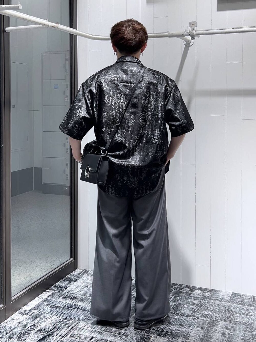 グレー系のスラックス、ブラック系のショルダーバッグ、ブラック系のサンダルを着用したメンズの夏コーディネートの2枚目の写真