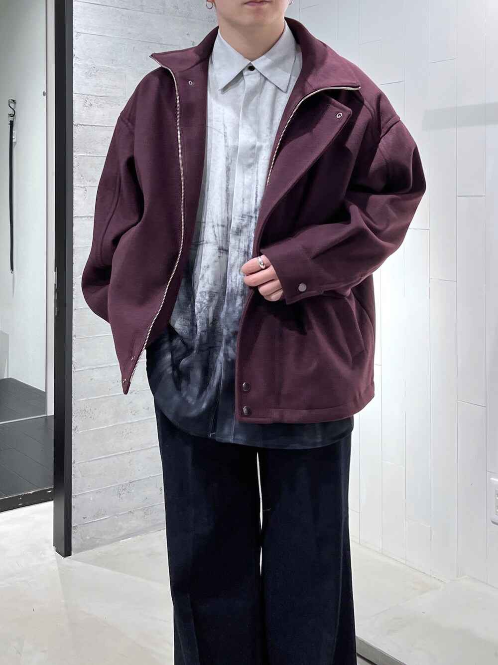 レッド系のブルゾン、ブルー系のデニムパンツ、ブラック系のブーツを着用したメンズの秋コーディネートの3枚目の写真