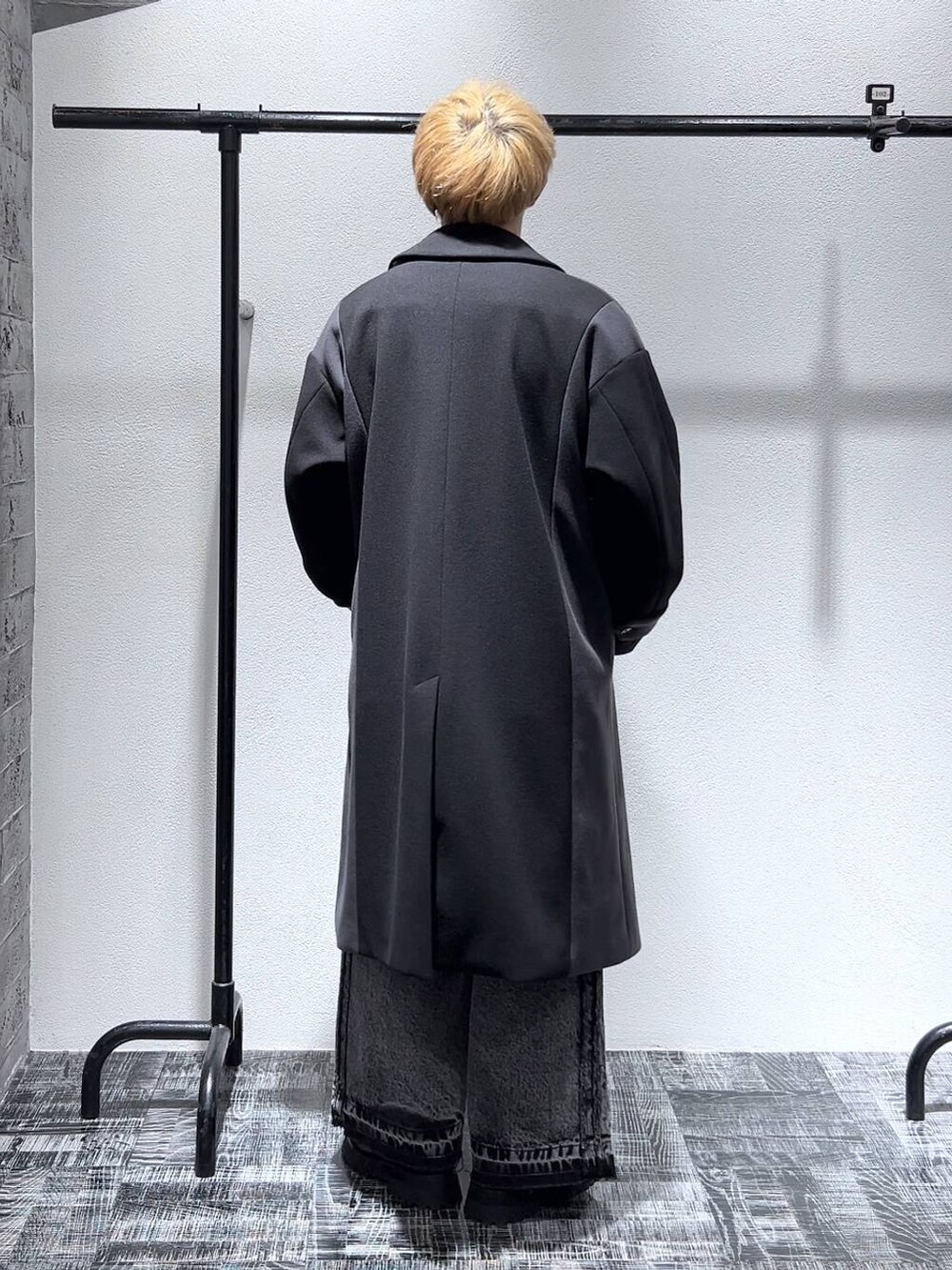 ブラック系のその他パンツ、ブラック系のブーツ、ブラック系のステンカラーコートを着用したメンズの冬コーディネートの3枚目の写真