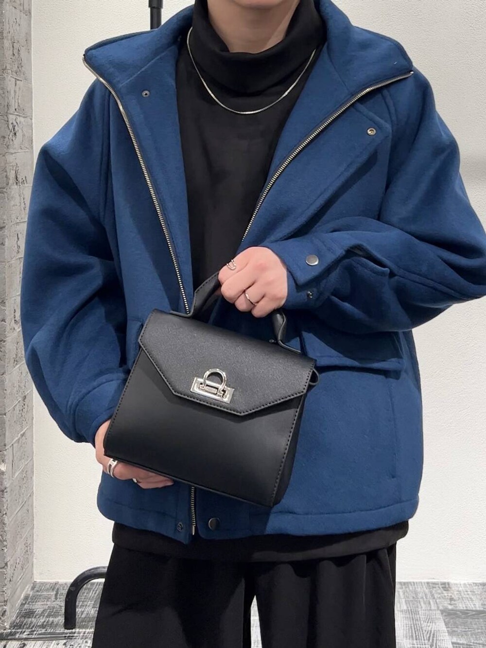 ブルー系のブルゾン、ブラック系のスラックス、ブラック系のショルダーバッグを着用したメンズの秋コーディネートの5枚目の写真