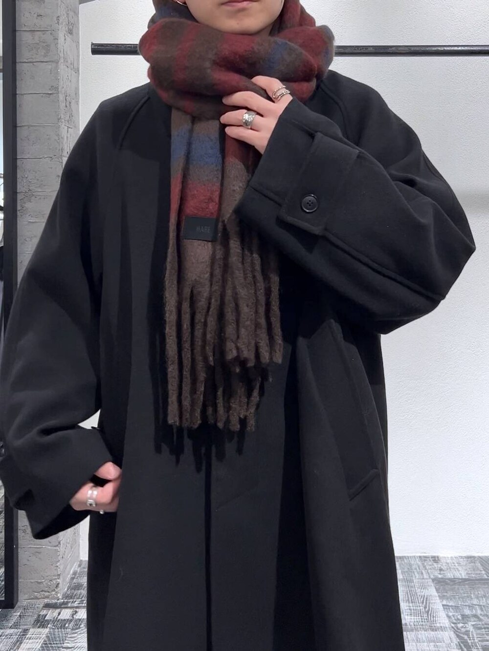 ブラック系のステンカラーコート、ブラック系のデニムパンツ、ブラック系のブーツを着用したメンズの冬コーディネートの5枚目の写真