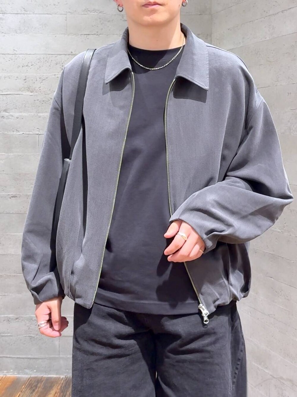 ブラック系のデニムパンツ、ブラック系のドレスシューズ、ブラック系のショルダーバッグを着用したメンズの秋コーディネートの5枚目の写真