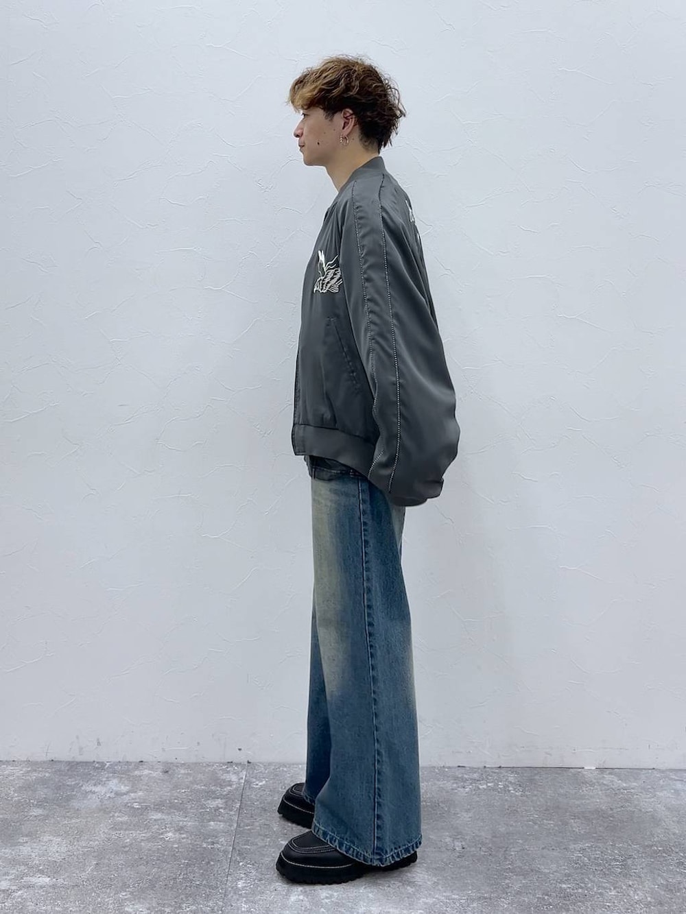 ブルー系のデニムパンツ、ブラック系のドレスシューズ、グレー系のスカジャンを着用したメンズの秋コーディネートの4枚目の写真