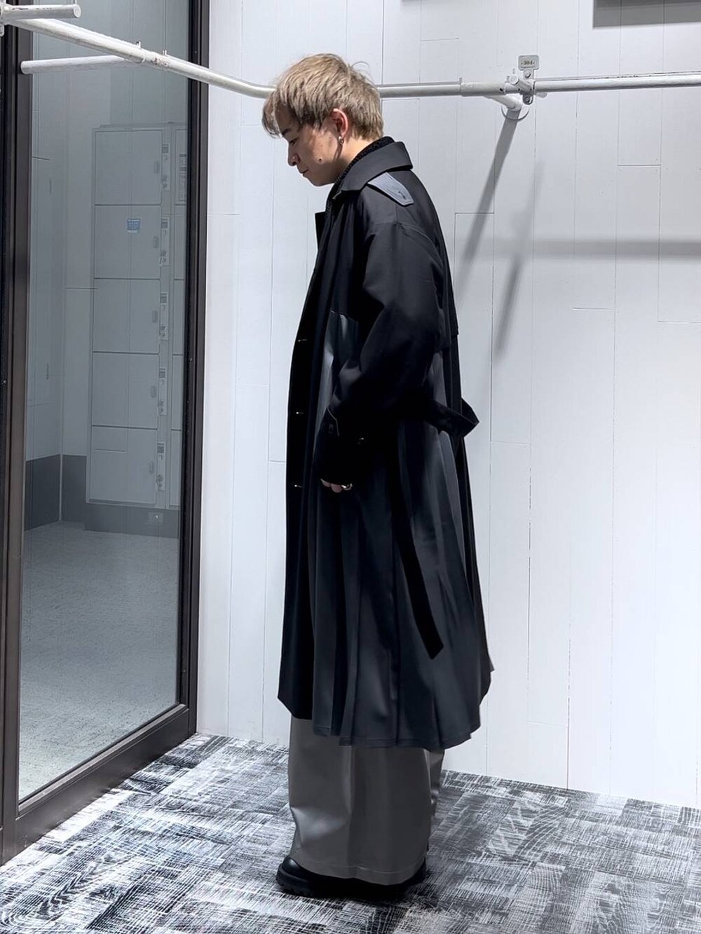 ブラック系のステンカラーコート、ブラック系のニット/セーター、シルバー系のリングを着用したメンズの秋コーディネートの4枚目の写真