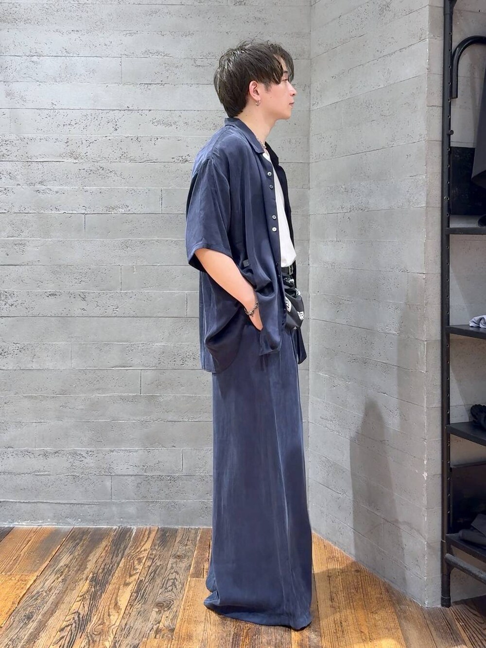 ブルー系のスラックス、ブラック系のサンダル、ホワイト系のTシャツ/カットソーを着用したメンズの夏コーディネートの2枚目の写真