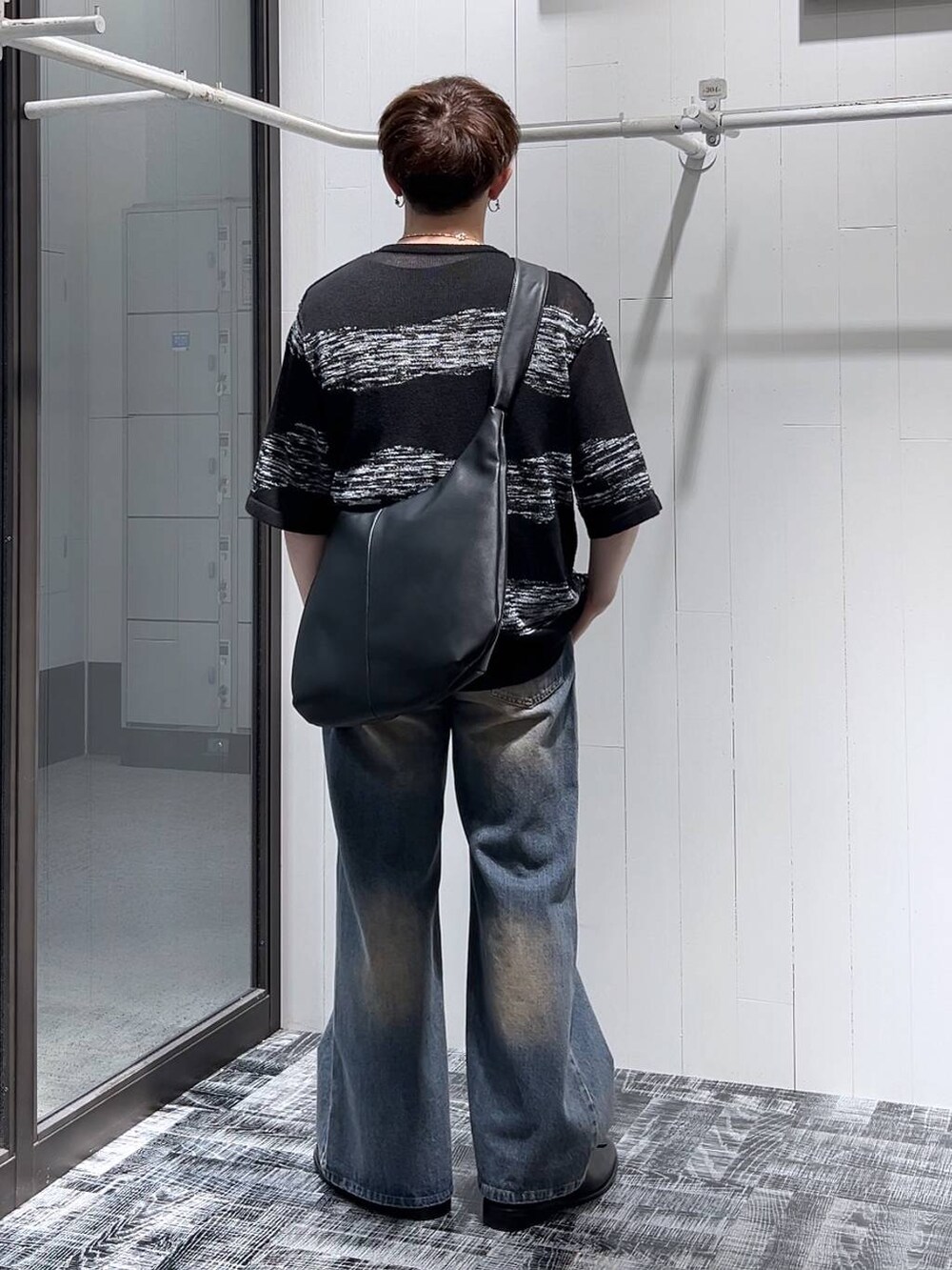 ブルー系のデニムパンツ、ブラック系のショルダーバッグ、ブラック系のニット/セーターを着用したメンズの夏コーディネートの3枚目の写真