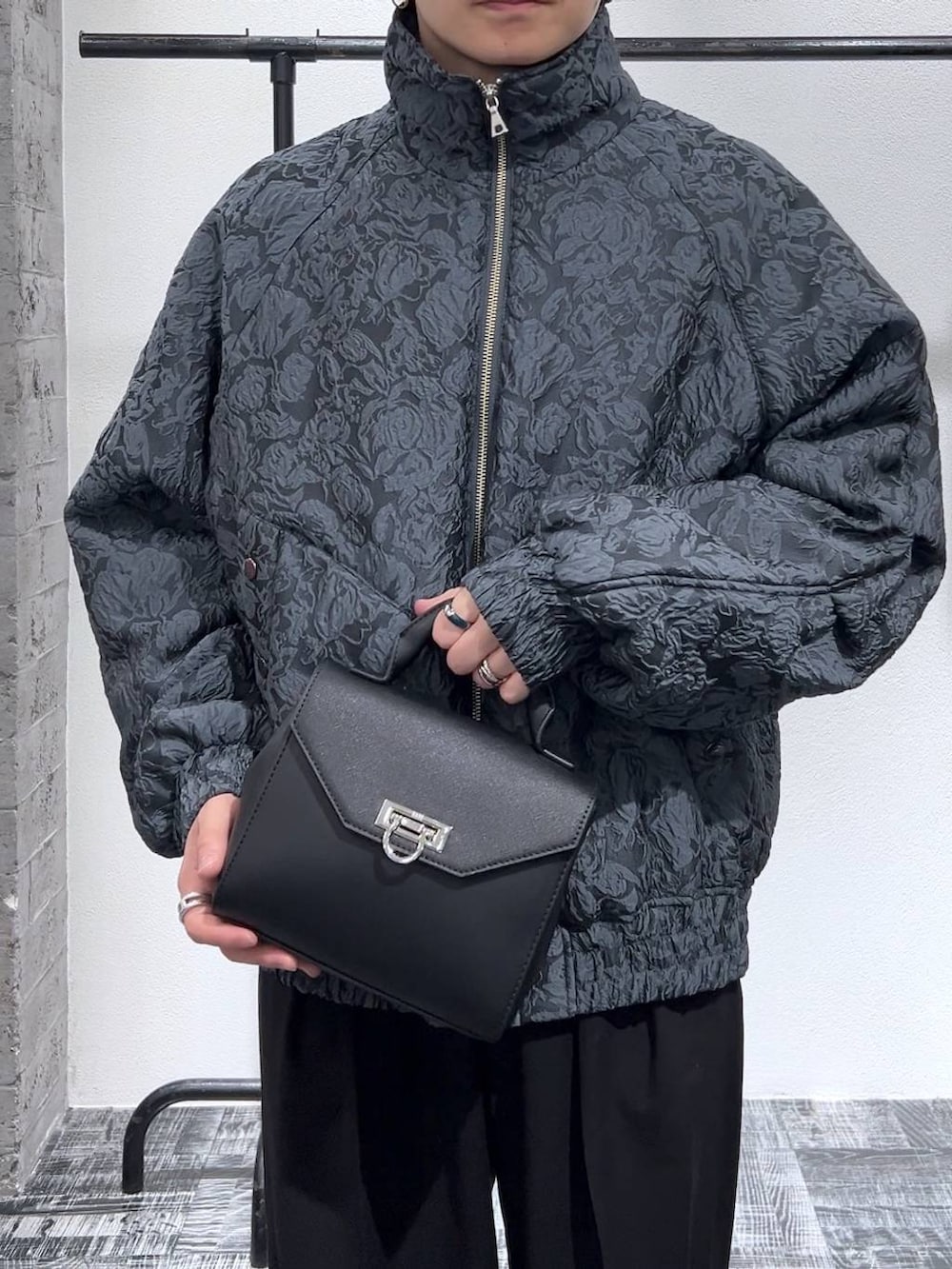 ブラック系のドレスシューズ、ブラック系のショルダーバッグ、ブラック系のスラックスを着用したメンズの冬コーディネートの5枚目の写真