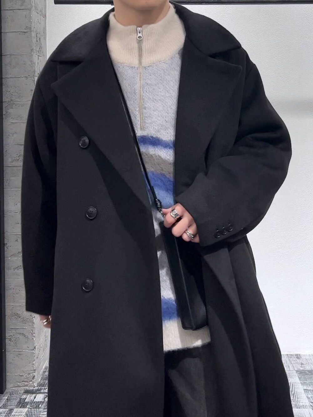 ブラック系のドレスシューズ、ブラック系のステンカラーコート、ブラック系のショルダーバッグを着用したメンズの冬コーディネートの5枚目の写真