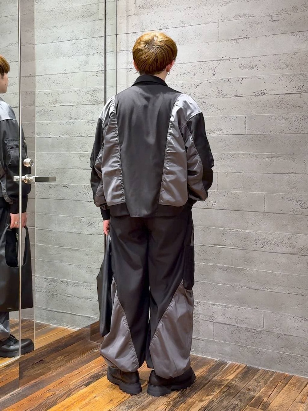 ブラック系のトートバッグ、ブラック系のTシャツ/カットソー、ブラック系のドレスシューズを着用したメンズの春コーディネートの3枚目の写真