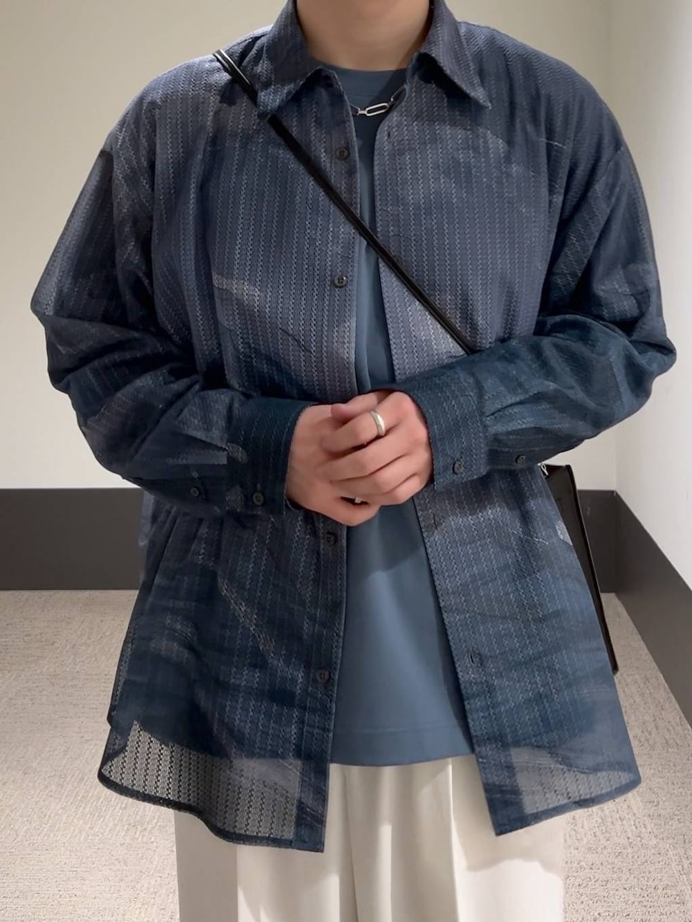 ホワイト系のスラックス、ブルー系のTシャツ/カットソー、ブラック系のショルダーバッグを着用したメンズの冬コーディネートの5枚目の写真