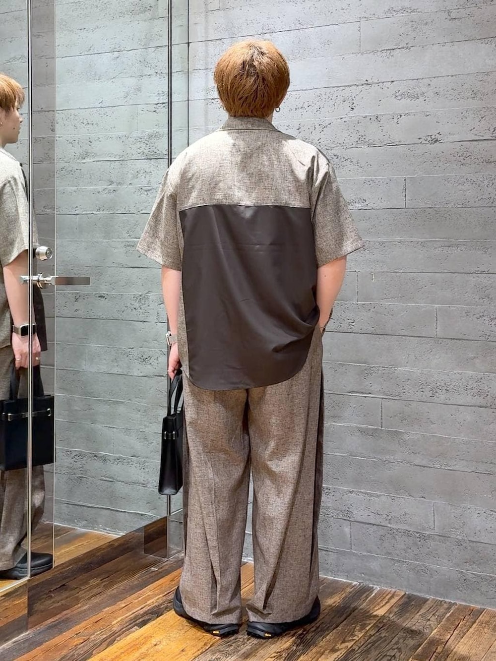 ブラック系のTシャツ/カットソー、ベージュ系のスラックス、ブラック系のショルダーバッグを着用したメンズの夏コーディネートの3枚目の写真