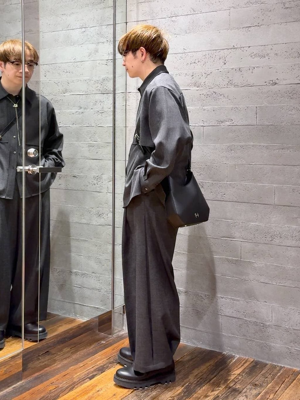 ブラック系のドレスシューズ、ブラック系のスラックス、ブラック系のショルダーバッグを着用したメンズの春コーディネートの4枚目の写真