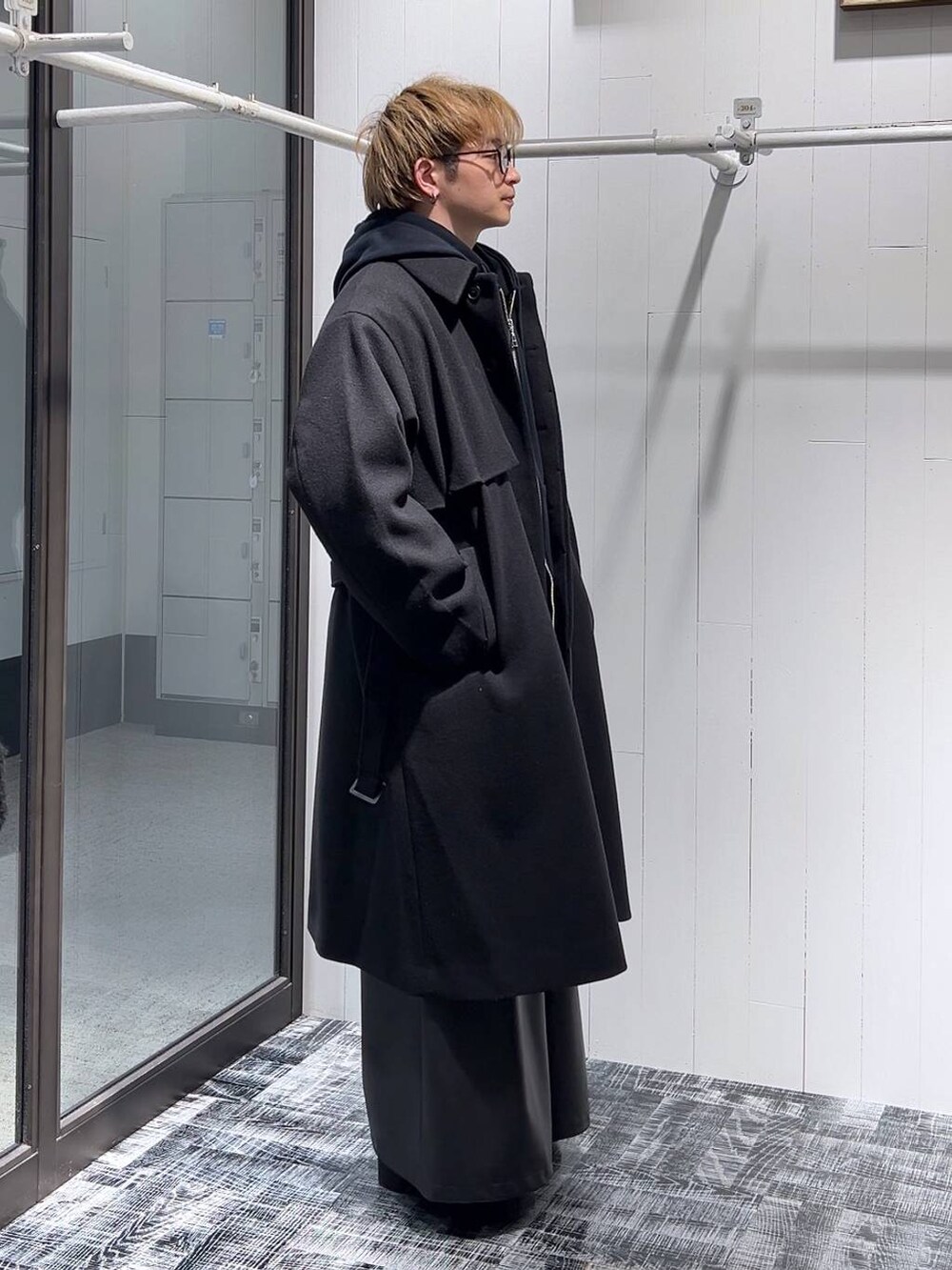 ブラック系のステンカラーコート、ブラック系のその他パンツ、ブラック系のパーカーを着用したメンズの冬コーディネートの2枚目の写真