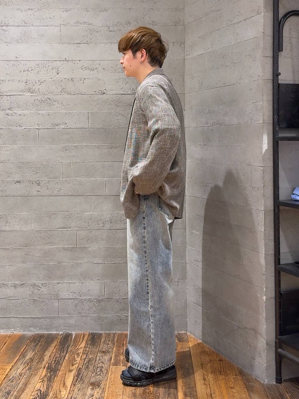 ブラック系のサンダル、グレー系のテーラードジャケット、ブルー系のデニムパンツを着用したメンズの春コーディネートの4枚目の写真