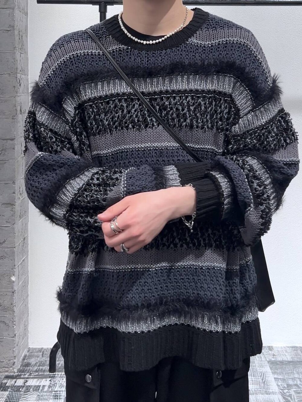 ブラック系のスニーカー、ブラック系のショルダーバッグ、ブラック系のニット/セーターを着用したメンズの春コーディネートの5枚目の写真