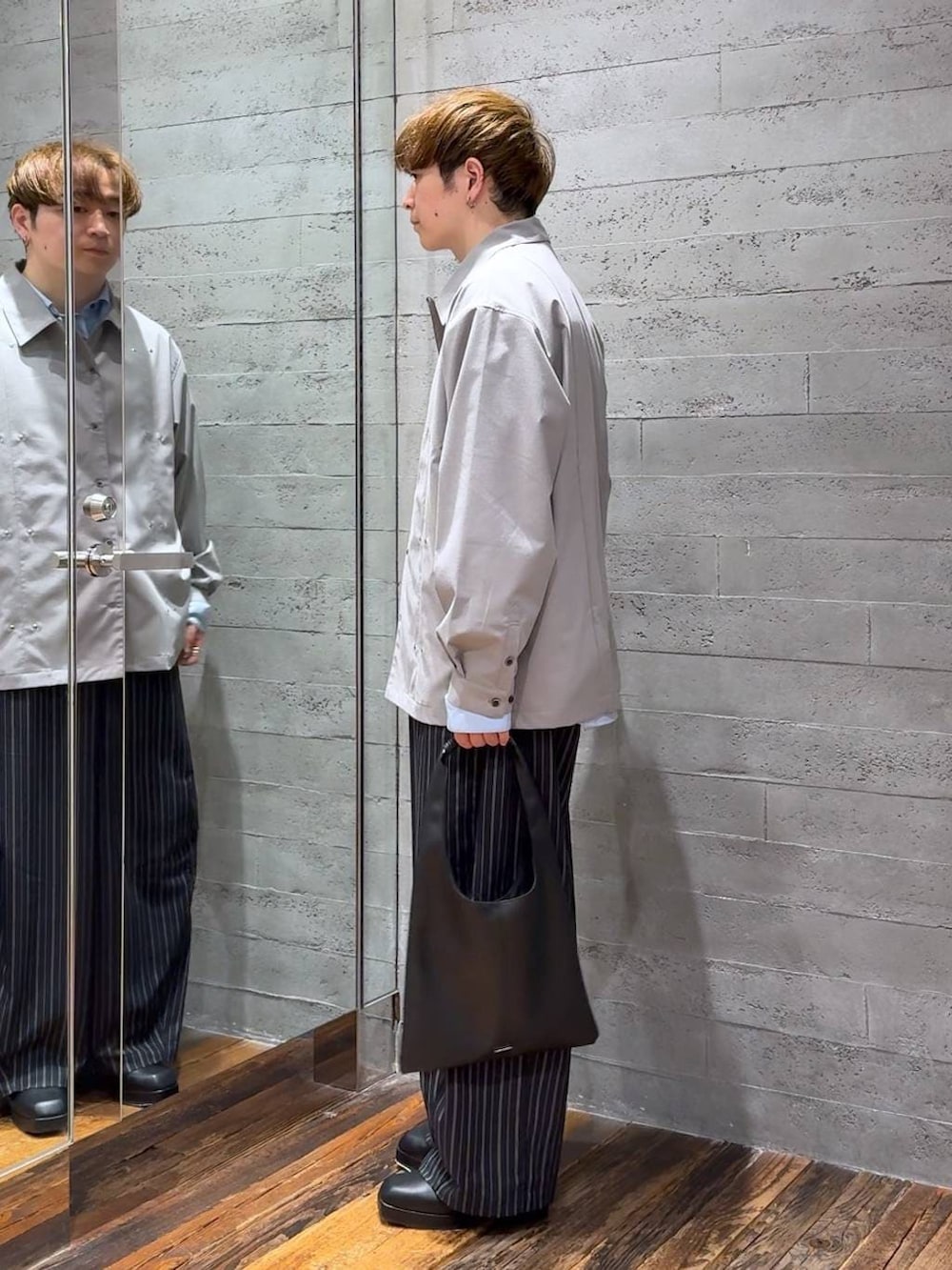 ブラック系のトートバッグ、ブラック系のブーツ、ブラック系のスラックスを着用したメンズの春コーディネートの4枚目の写真