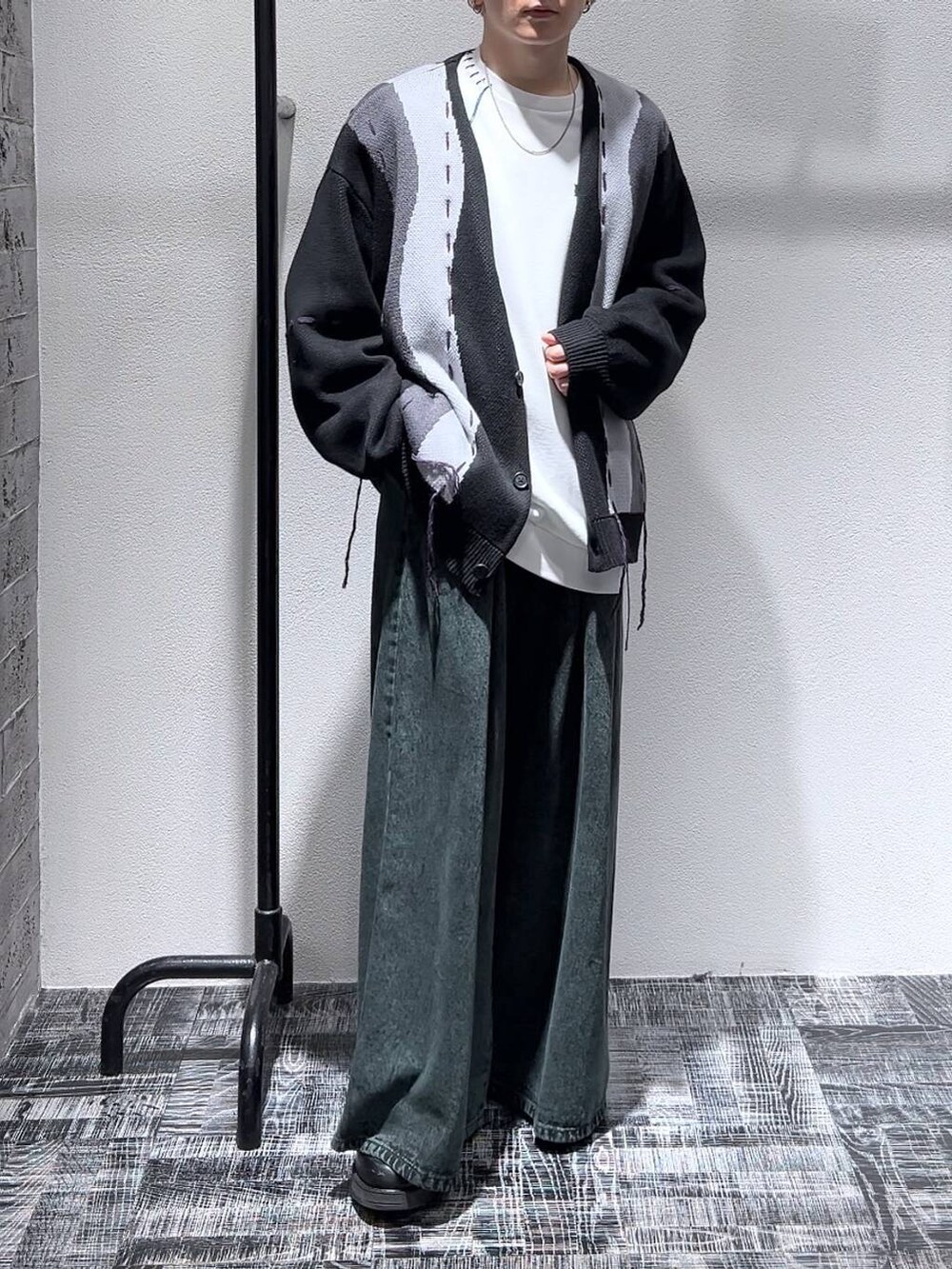 ブラック系のドレスシューズ、ブラック系のカーディガン/ボレロ、グリーン系のデニムパンツを着用したメンズの冬コーディネートの2枚目の写真