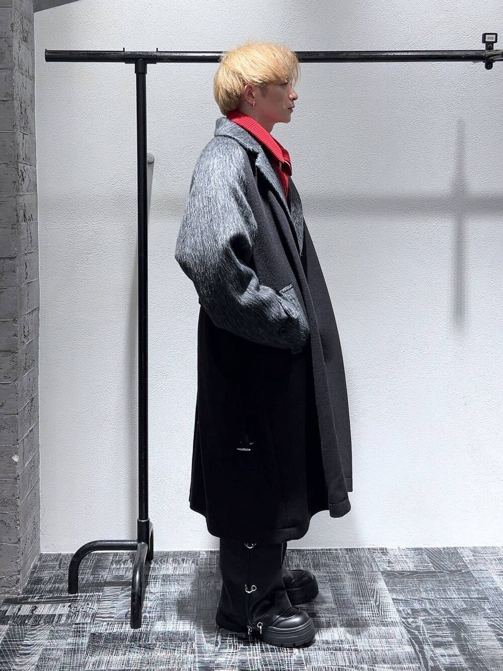 ブラック系のブーツ、ブラック系のダッフルコート、レッド系のニット/セーターを着用したメンズの秋コーディネートの3枚目の写真