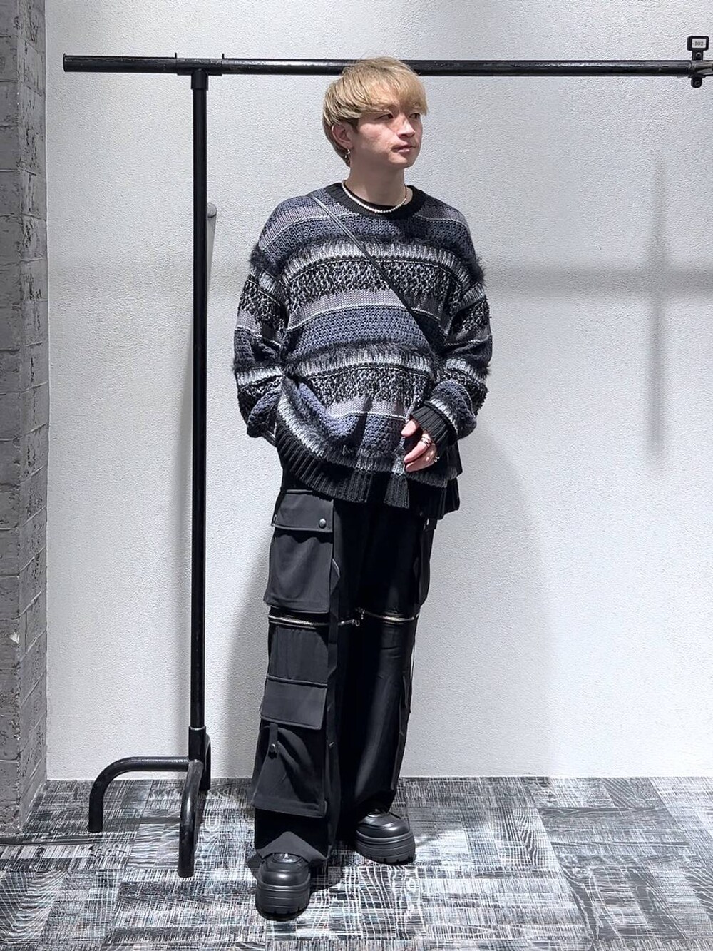 ブラック系のスニーカー、ブラック系のショルダーバッグ、ブラック系のニット/セーターを着用したメンズの春コーディネートの2枚目の写真