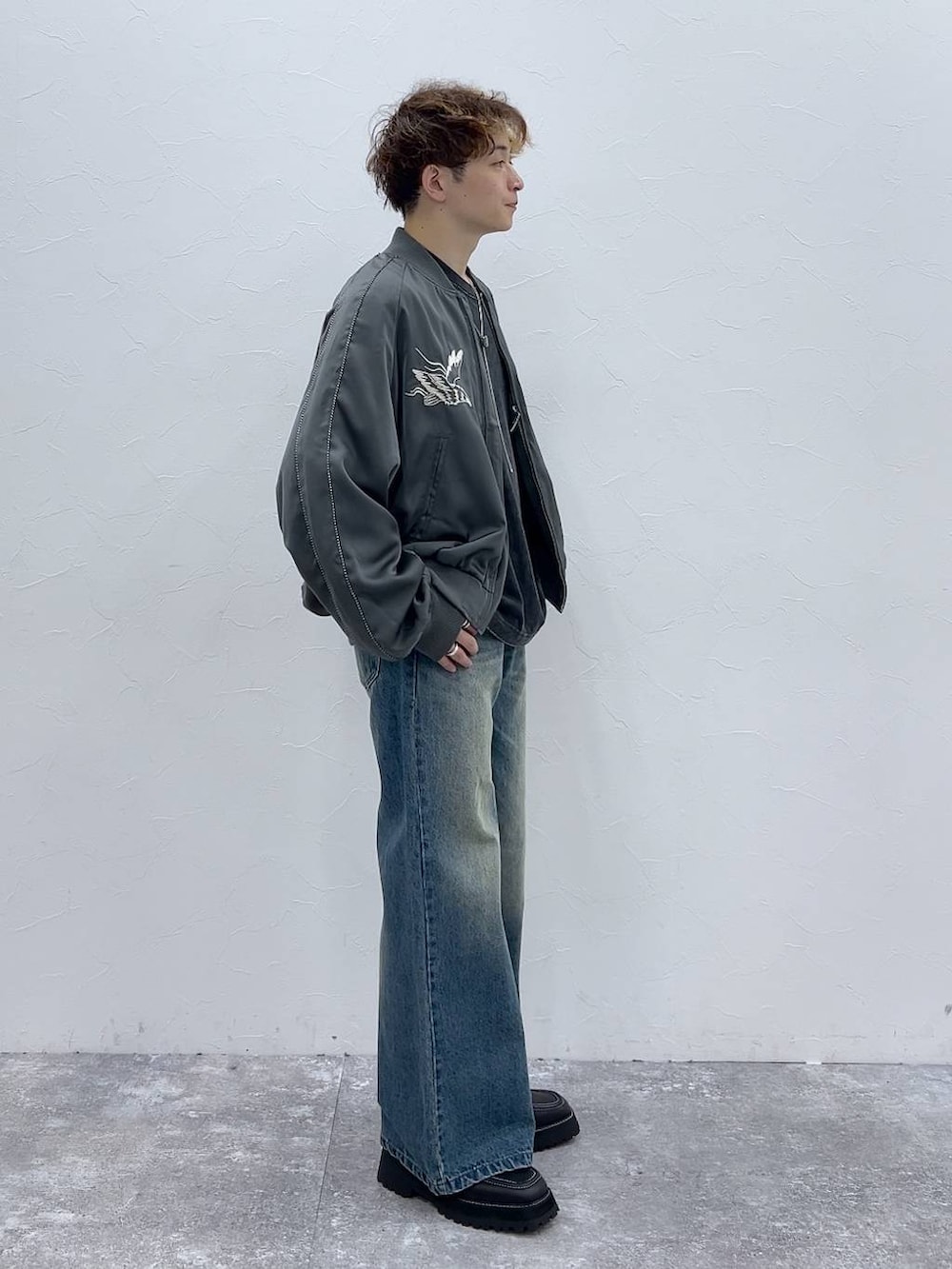 ブルー系のデニムパンツ、ブラック系のドレスシューズ、グレー系のスカジャンを着用したメンズの秋コーディネートの2枚目の写真