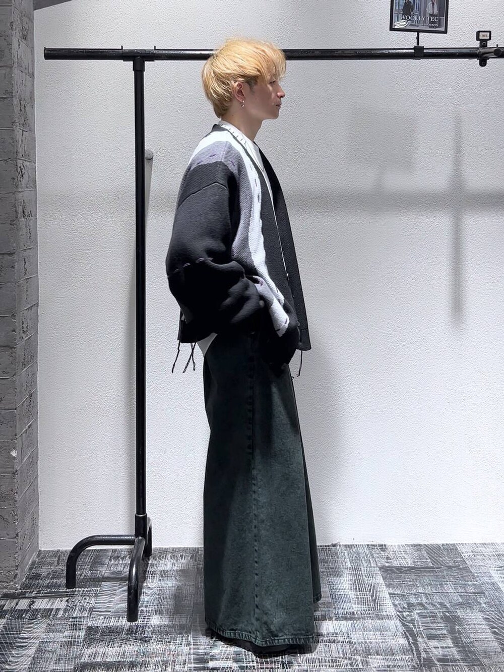 ブラック系のドレスシューズ、ブラック系のカーディガン/ボレロ、グリーン系のデニムパンツを着用したメンズの冬コーディネートの3枚目の写真