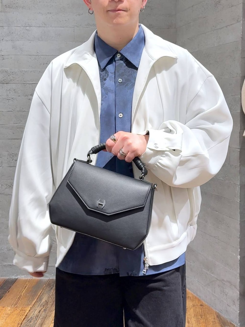 ブラック系のドレスシューズ、ブラック系のデニムパンツ、ホワイト系のブルゾンを着用したメンズの春コーディネートの5枚目の写真