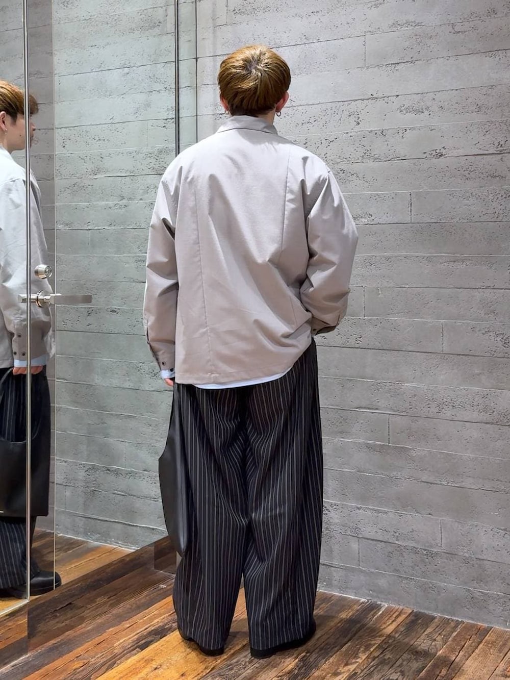 ブラック系のトートバッグ、ブラック系のブーツ、ブラック系のスラックスを着用したメンズの春コーディネートの3枚目の写真