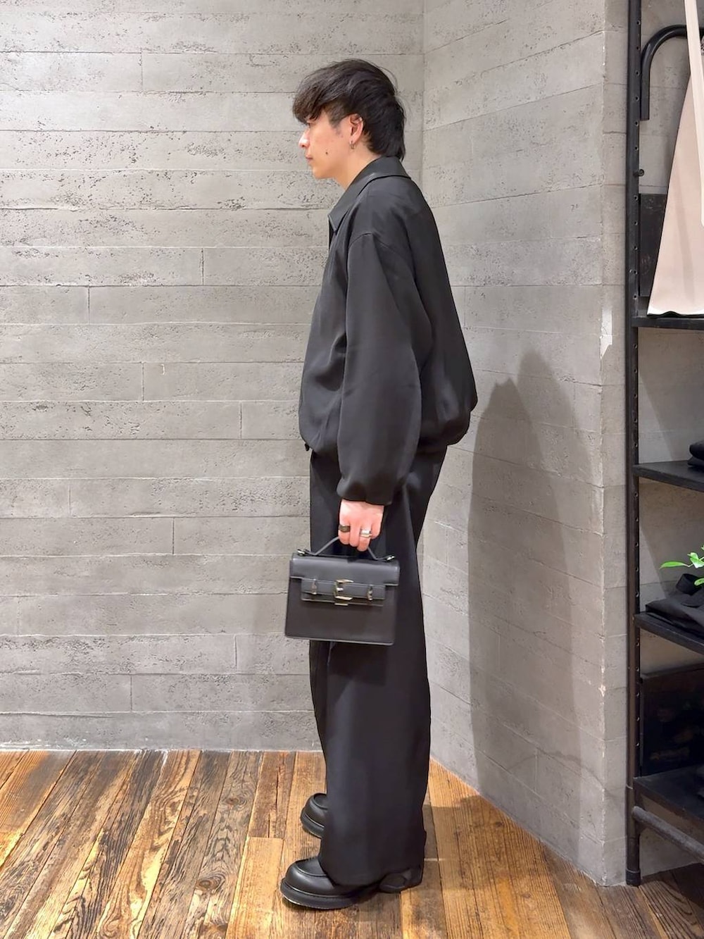 ブラック系のローファー、ブラック系のハンドバッグ、グレー系のポロシャツを着用したメンズの冬コーディネートの3枚目の写真