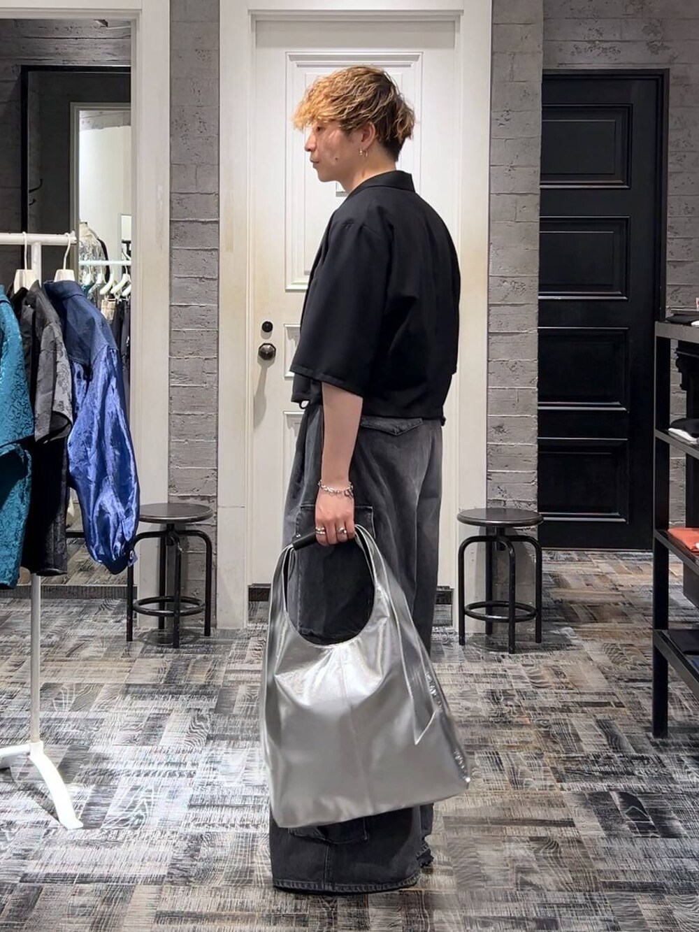 シルバー系のトートバッグ、グレー系のTシャツ/カットソー、ブラック系のサンダルを着用したメンズの夏コーディネートの2枚目の写真