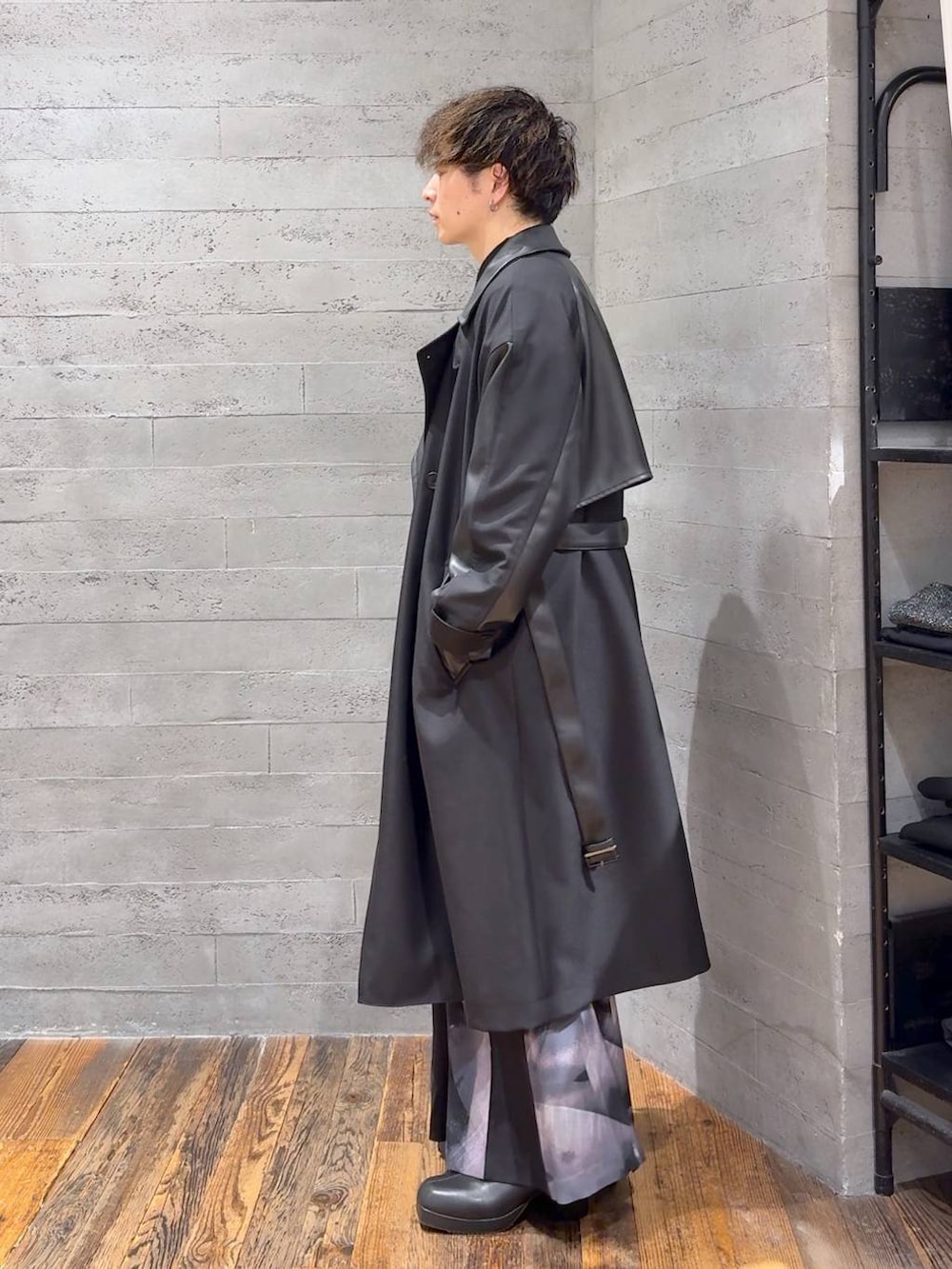 ブラック系のトレンチコート、ブラック系のブーツ、シルバー系のネックレスを着用したメンズの秋コーディネートの4枚目の写真