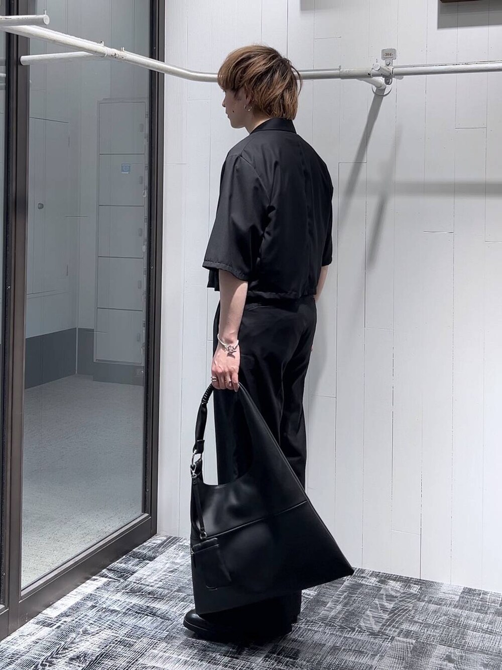 ブラック系のドレスシューズ、ブラック系のトートバッグ、ブラック系のTシャツ/カットソーを着用したメンズの春コーディネートの3枚目の写真