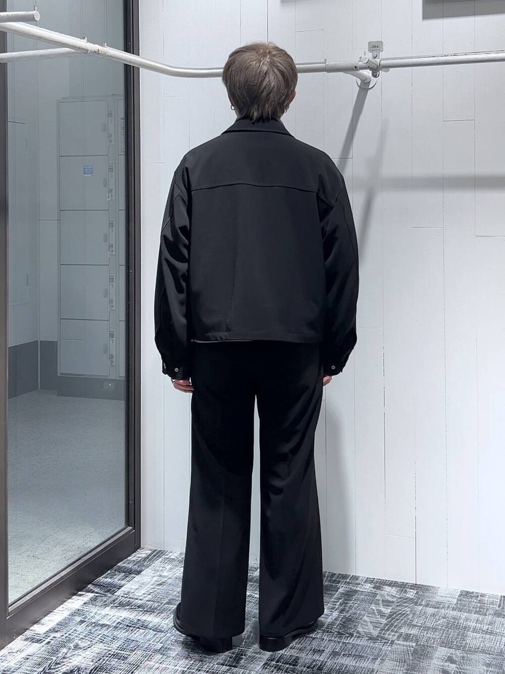 グレー系のスウェット、ブラック系のスラックス、ブラック系のドレスシューズを着用したメンズの冬コーディネートの3枚目の写真